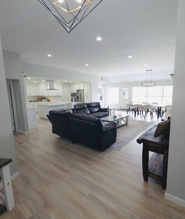 Living room featuring light wood finished floors, a chandelier, and recessed lighting | Image 5