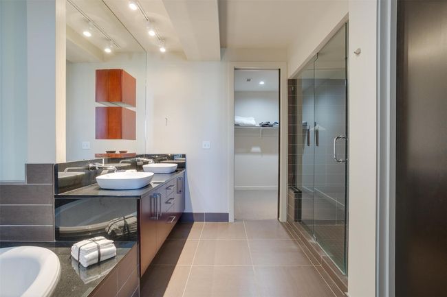 Full bathroom with double vanity, a shower stall, tile patterned flooring, track lighting, and a spacious closet | Image 32
