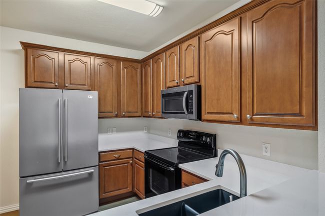 Kitchen featuring light countertops, brown cabinets, stainless steel appliances, and a sink. Refrigerator will convey | Image 11