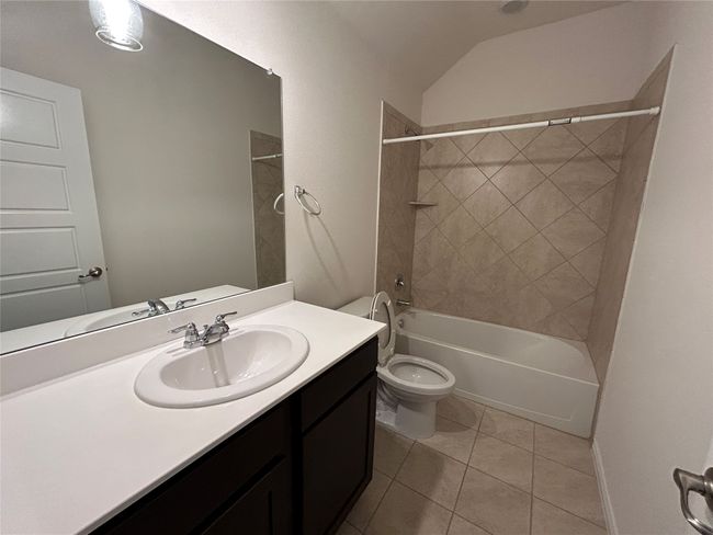 Bathroom with tile patterned flooring, toilet, vanity, shower / tub combination, and lofted ceiling | Image 13