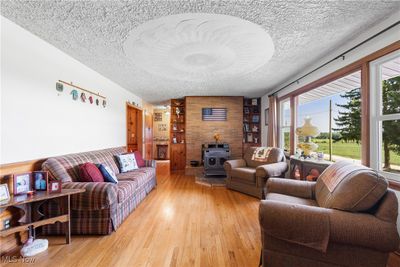 Living room with a wood stove, and light hardwood / wood-style floors. | Image 3