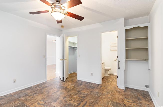 Unfurnished bedroom featuring ceiling fan, a spacious closet, ensuite bath, and a closet | Image 10