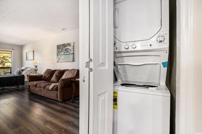 Laundry room featuring stacked washer / dryer, wood finished floors, and a textured ceiling | Image 11