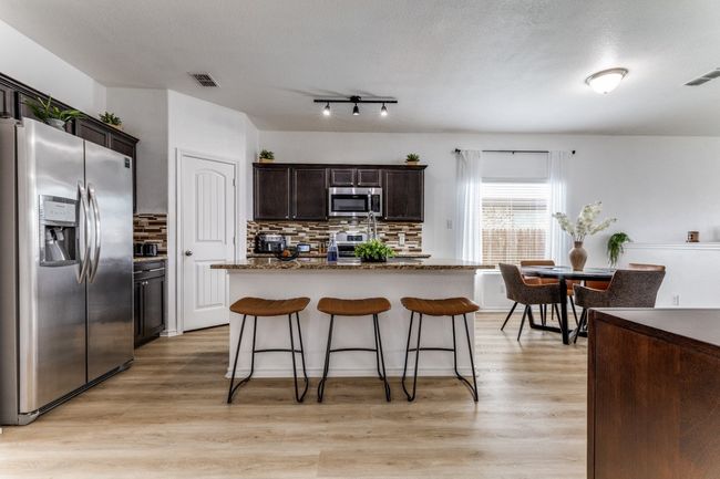 Kitchen featuring stainless steel appliances, decorative backsplash, a kitchen bar, and light wood-type flooring | Image 12
