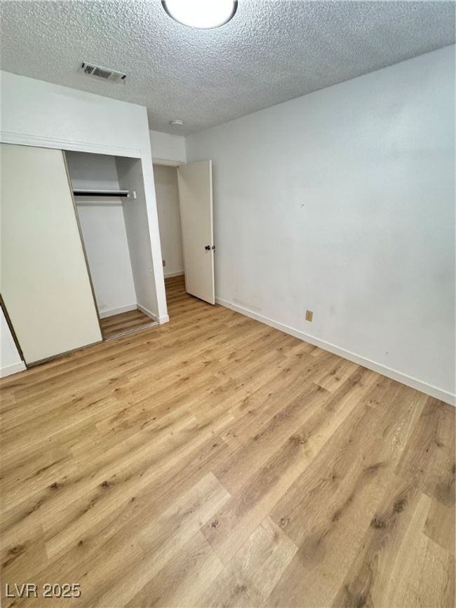 Unfurnished bedroom with light wood finished floors, a closet, and a textured ceiling | Image 33