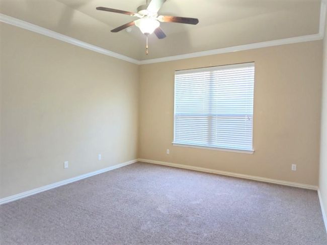 Carpeted spare room with ceiling fan, ornamental molding, baseboards, and a tray ceiling | Image 26