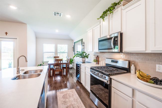 Kitchen with appliances with stainless steel finishes, dark wood-style flooring, tasteful backsplash, light countertops, and white cabinets | Image 15