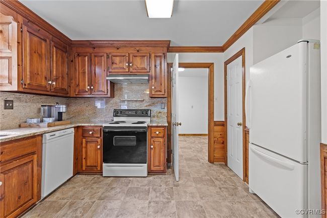 Kitchen featuring white appliances, under cabinet range hood, tasteful backsplash, and brown cabinets | Image 10