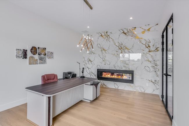 Office area featuring a marble fireplace wall, recessed and custom lighting, light wood finished floors, glass wall/door | Image 10