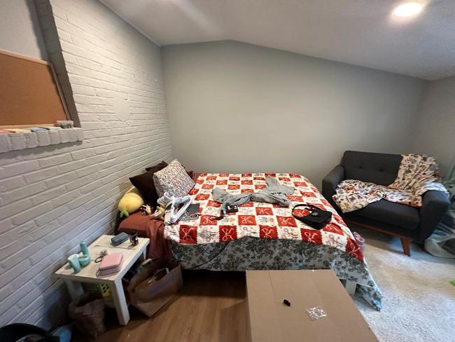 Bedroom with vaulted ceiling, carpet flooring, and brick wall | Image 6