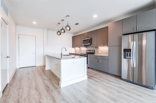 Kitchen with stainless steel appliances, backsplash, light wood finished floors, light stone countertops, and recessed lighting | Image 5