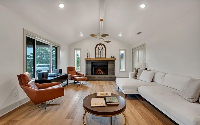 Living area featuring light wood-style flooring, a fireplace, and recessed lighting | Image 7