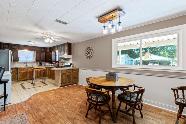 Dining room with ceiling fan, ornamental molding, and light wood finished floors | Image 7
