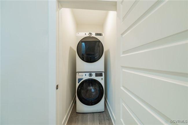 Laundry area featuring stacked washer and clothes dryer, wood finished floors, and baseboards | Image 27