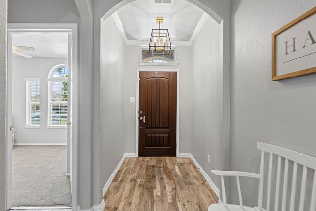 Foyer entrance with wood like tile floors, a chandelier, ornamental molding, and arched walkways | Image 4