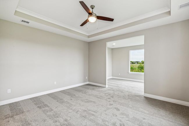 Carpeted empty room with ceiling fan, ornamental molding, and a tray ceiling | Image 8
