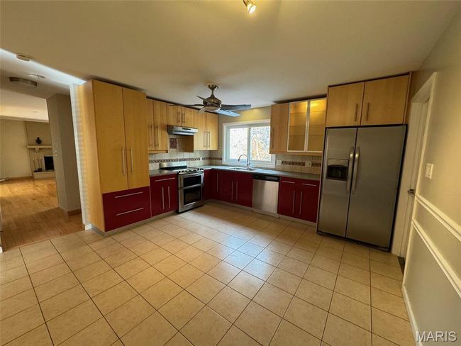 Kitchen with stainless steel appliances, sink, ceiling fan, light tile patterned flooring, and backsplash | Image 8