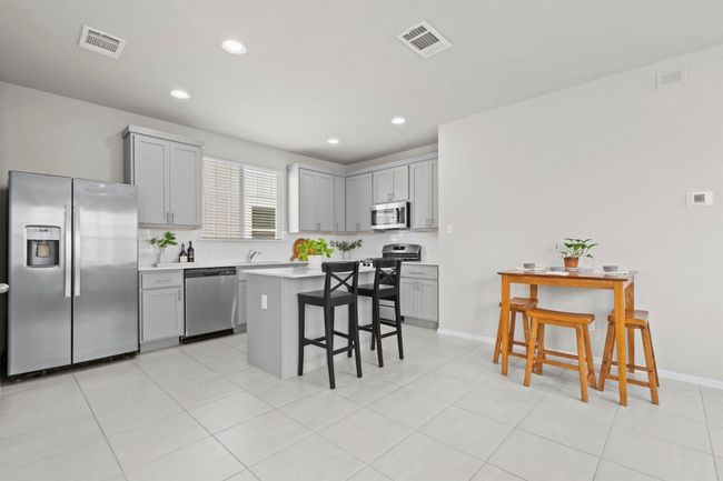 Kitchen featuring appliances with stainless steel finishes, a breakfast bar, gray cabinetry, light countertops, and recessed lighting | Image 5