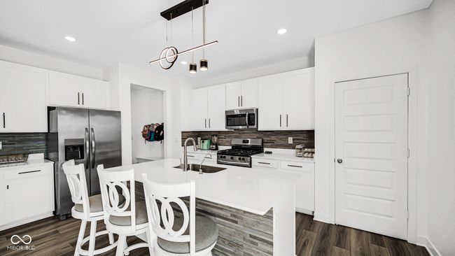 kitchen featuring stainless steel appliances, a sink, backsplash, dark wood-type flooring, and a breakfast bar area | Image 16