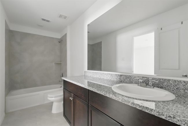 Bathroom with tile patterned floors, vanity, toilet, shower / bathtub combination, and visible vents | Image 7