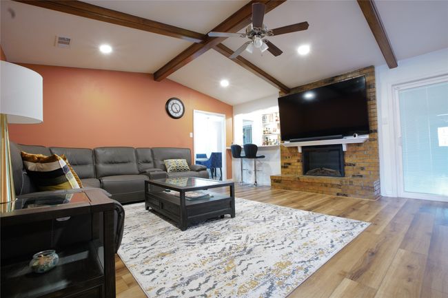 Living area featuring a ceiling fan, wood finished floors, and a fireplace | Image 9