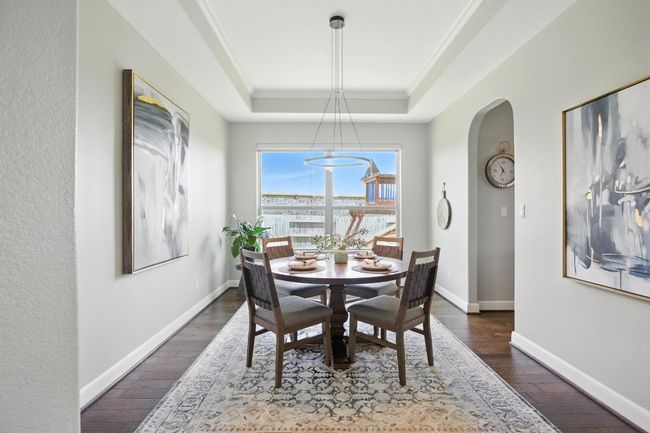 Dining area featuring a raised ceiling, arched walkways, dark wood-type flooring, and crown molding | Image 10