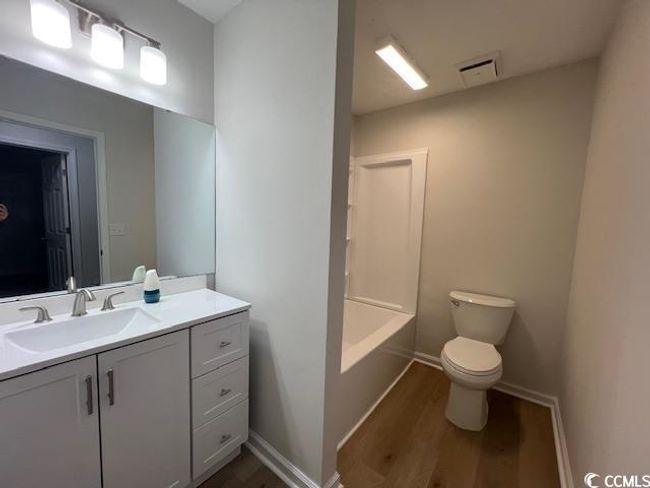 Full bathroom with vanity, toilet, baseboards, wood finished floors, and visible vents | Image 18