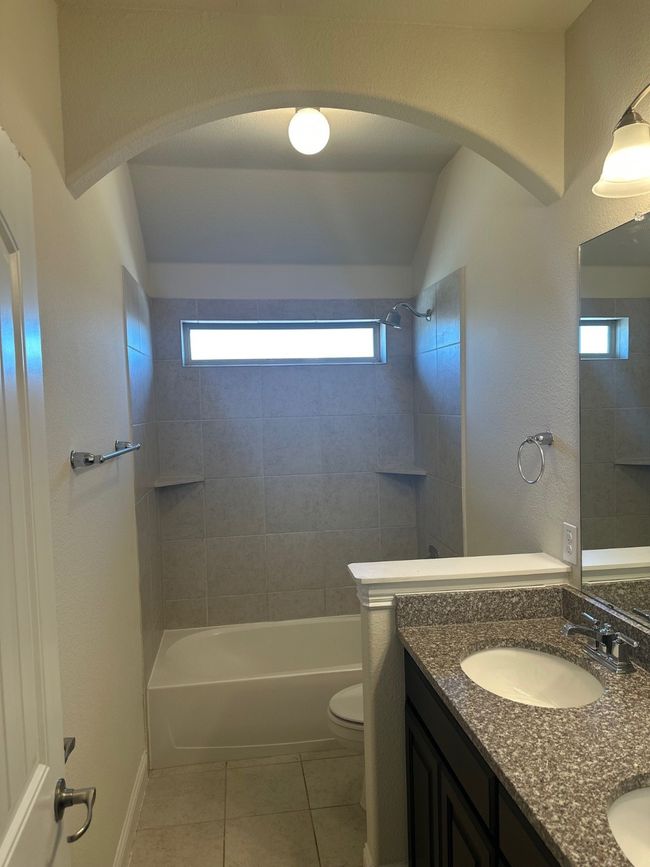 Bathroom featuring tile patterned flooring, toilet, a sink, shower / bathing tub combination, and double vanity | Image 21