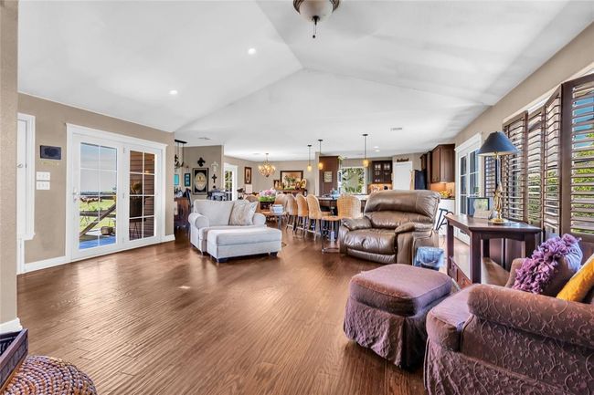 Living room with lofted ceiling, dark wood-style floors, healthy amount of natural light, recessed lighting, and a chandelier | Image 6