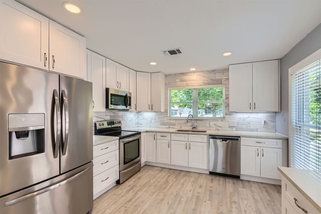 Kitchen featuring stainless steel appliances, light countertops, backsplash, and recessed lighting | Image 5