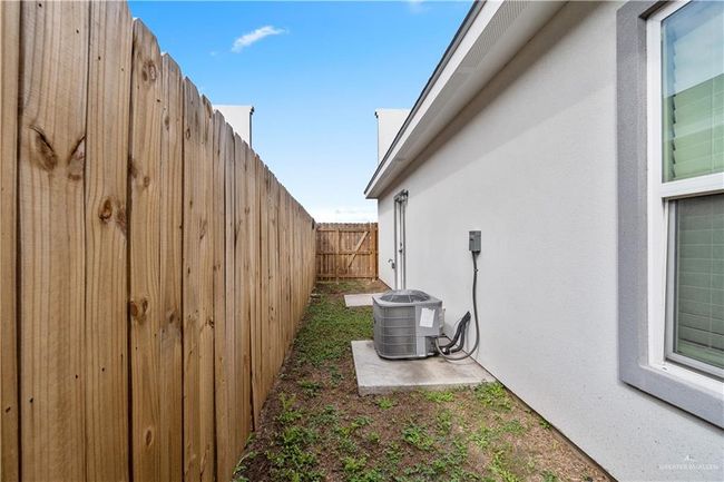 View of property exterior with central AC unit, stucco siding, and a fenced backyard | Image 15