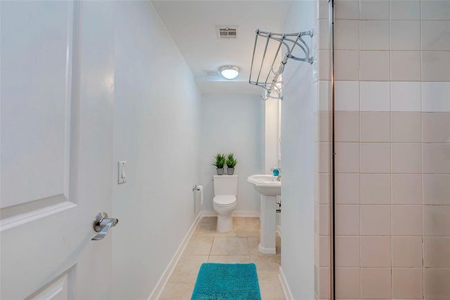 Elegant secondary bathroom featuring tile floors, a full shower, and a stylish pedestal sink. | Image 15