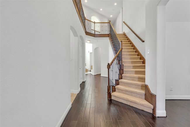 Stairway featuring arched walkways, a high ceiling, recessed lighting, and wood finished floors | Image 9