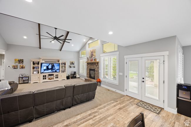 Living area featuring wood finished floors, ceiling fan, baseboards, a stone fireplace, and vaulted ceiling | Image 7
