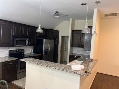 Kitchen with light hardwood / wood-style flooring, kitchen peninsula, backsplash, sink, and appliances with stainless steel finishes | Image 3