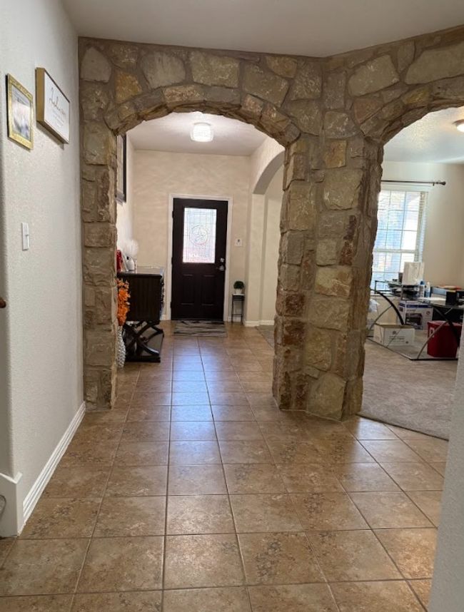 Tiled entryway featuring arched walkways and baseboards. | Image 7