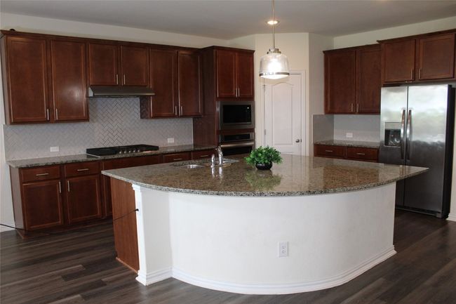 Kitchen with appliances with stainless steel finishes, dark wood-type flooring, a sink, an island with sink, and backsplash | Image 16