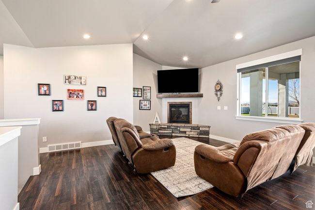 Living area featuring visible vents, baseboards, a fireplace, wood finished floors, and vaulted ceiling | Image 9