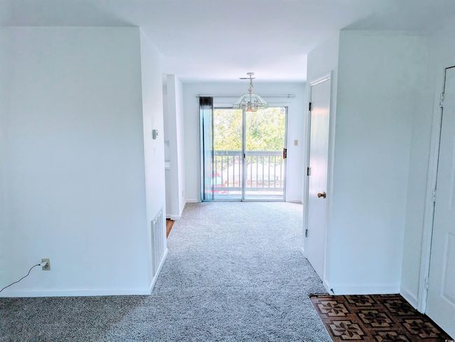 Hall with a chandelier and carpet floors | Image 5