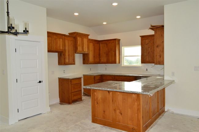 Kitchen with a peninsula, brown cabinetry, stone counters, recessed lighting, and lofted ceiling | Image 11