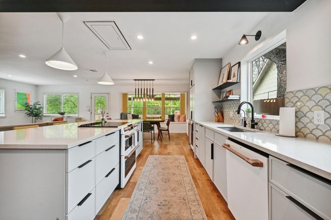 Stunning contemporary custom cabinetry by Cabico Cabinets with extensive storage space and built-in pantry storage plus a picture window addition over the sink. | Image 12