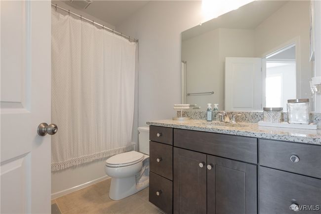 Bathroom with shower / tub combo with curtain, vanity, tile patterned flooring, and toilet | Image 37