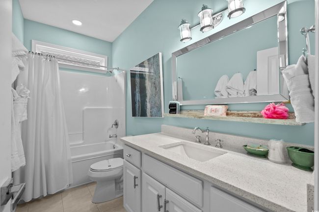 Bathroom featuring tile patterned floors, shower / bathtub combination with curtain, vanity, and toilet | Image 20