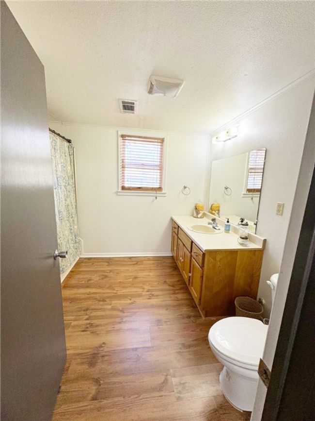 Bathroom featuring toilet, a textured ceiling, wood finished floors, and visible vents | Image 11