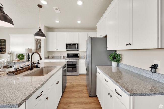 Kitchen featuring appliances with stainless steel finishes, a sink, recessed lighting, white cabinets, and light wood-style floors | Image 12