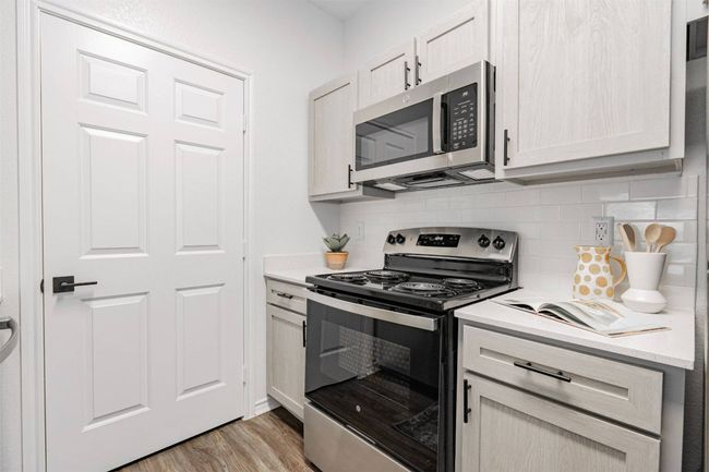 Kitchen featuring light hardwood / wood-style flooring, backsplash, and appliances with stainless steel finishes | Image 6