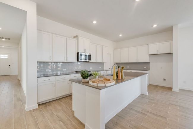 Kitchen with appliances with stainless steel finishes, dark countertops, light wood-style floors, tasteful backsplash, and recessed lighting | Image 7