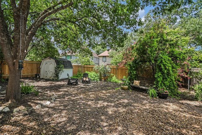 Backyard features another arched trellis, storage shed, and some recent fencing. | Image 19