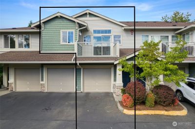 A great view of the townhome, garage with parking in front of the garage and the balcony. | Image 1