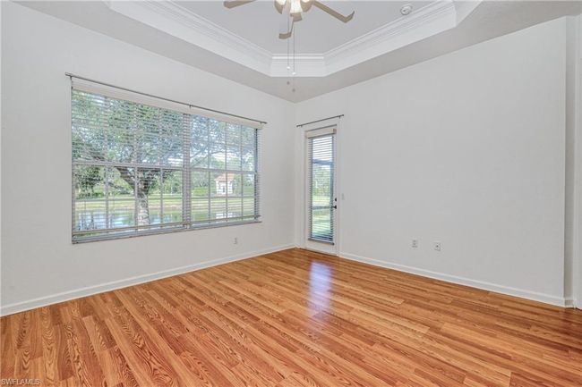 Unfurnished room featuring ceiling fan, ornamental molding, a tray ceiling, and light hardwood / wood-style floors | Image 34